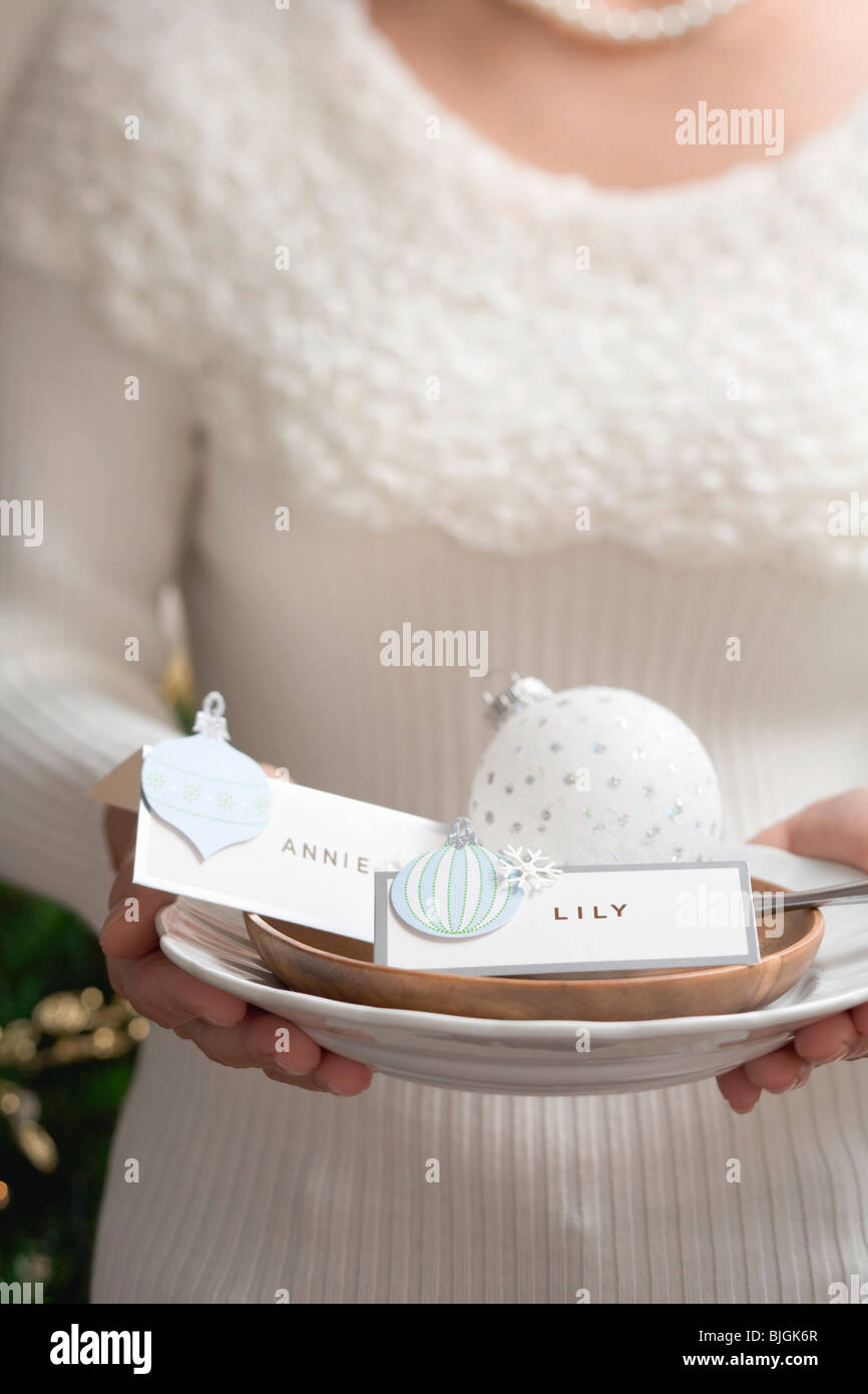 Woman holding plate and dish with place cards (Christmas) - Stock Photo