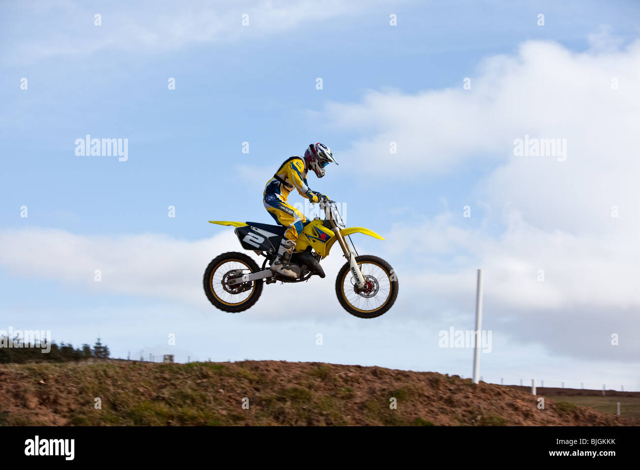 A rider on a yellow Suzuki motocross bike jumping in the air Stock Photo
