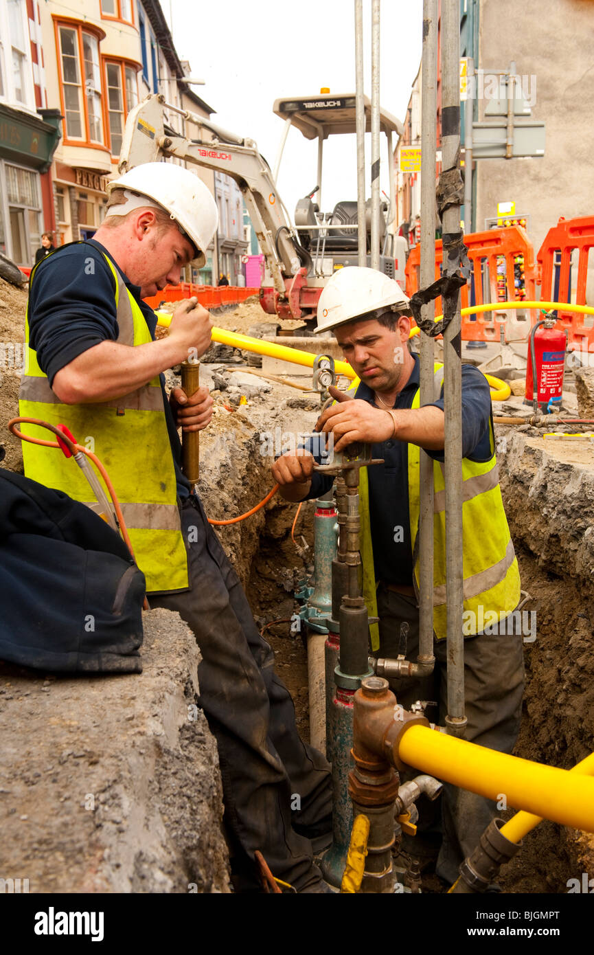 British Gas engineers replacing a steel gas supply main with a yellow plastic pipe alternative, UK Stock Photo