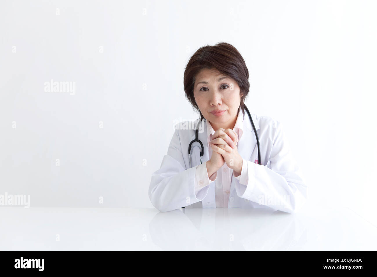Doctor sitting with hands clasped Stock Photo