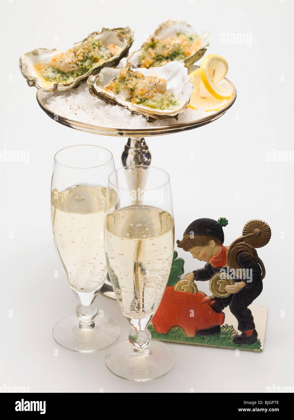 Oysters au gratin, glasses of sparkling wine & lucky charm - Stock Photo