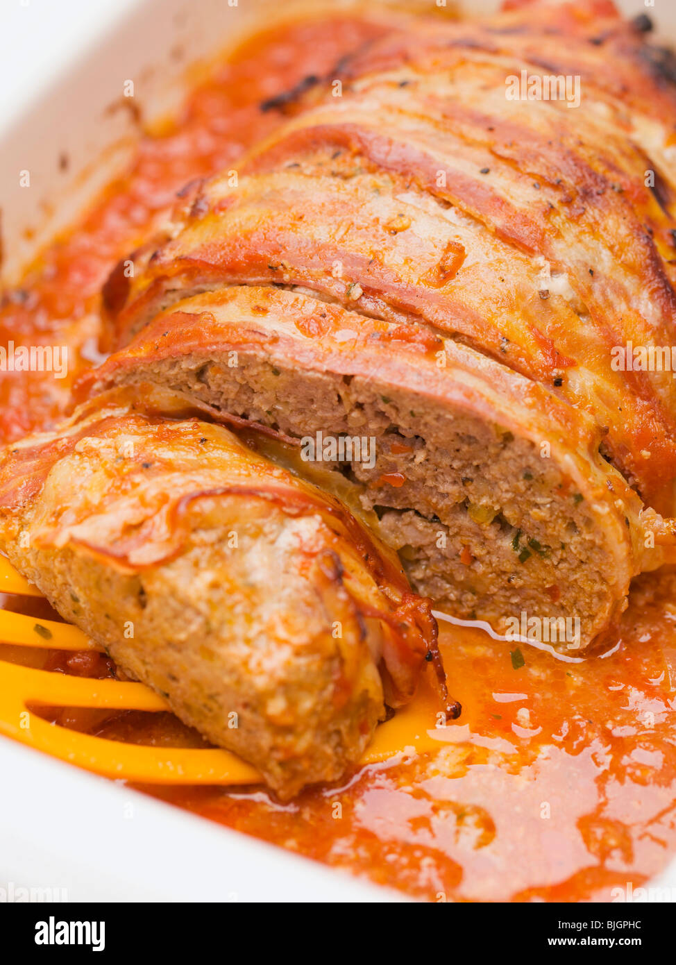 Baconwrapped meatloaf in tomato sauce Stock Photo Alamy