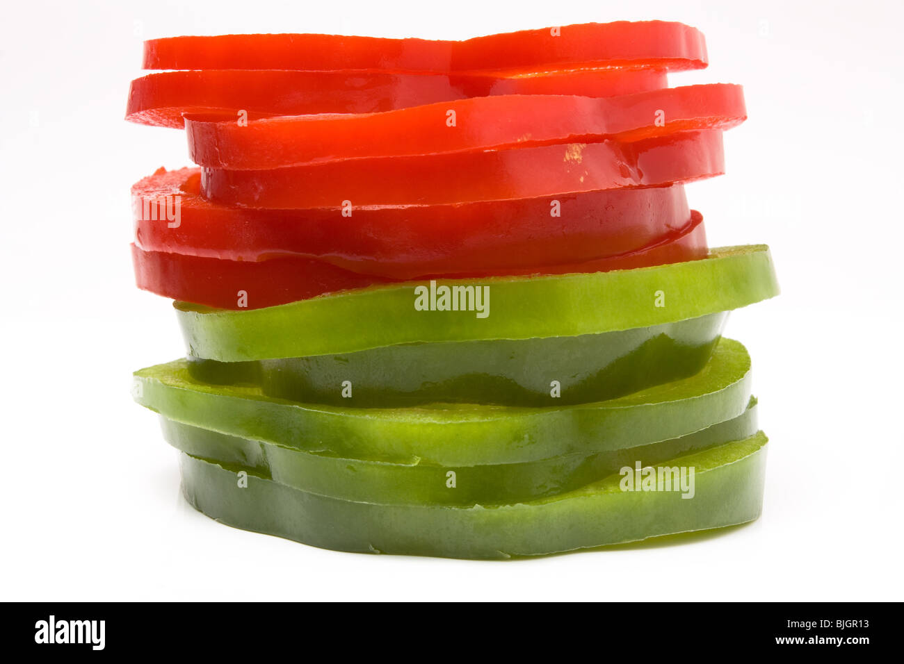 Stack of Sliced Red and Green Peppers arranged on white background. Stock Photo