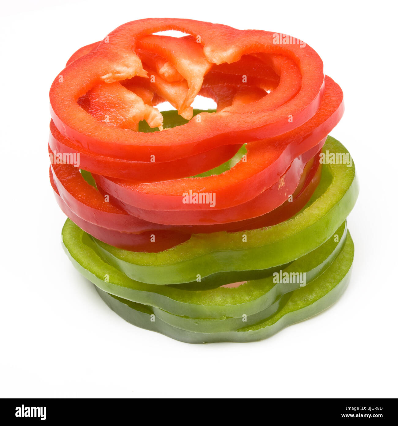 Stack of Sliced Red and Green Peppers arranged on white background. Stock Photo