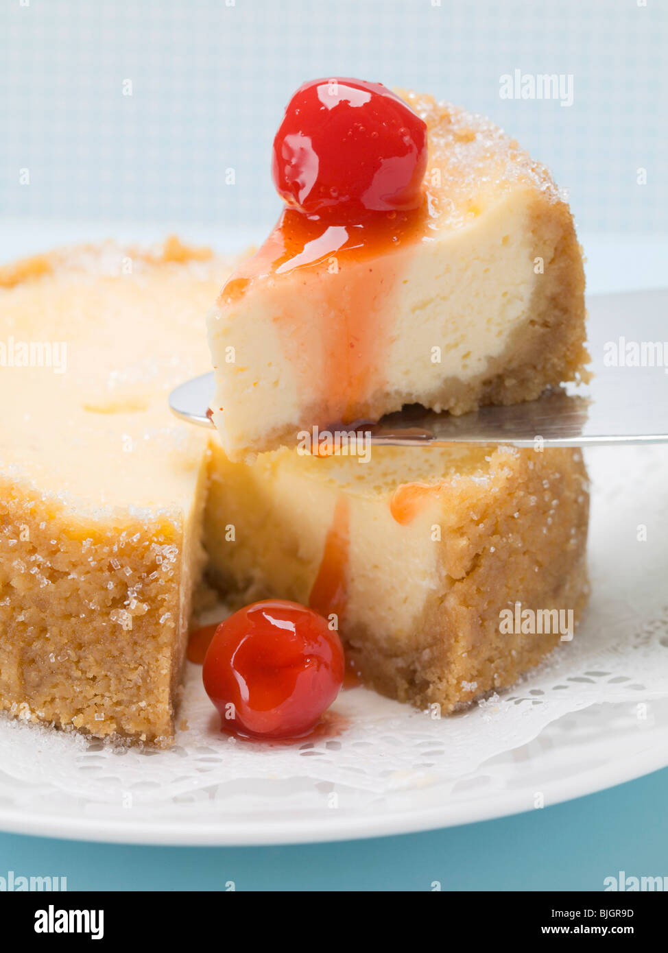 Small cheesecake with cocktail cherries, one piece on server Stock Photo Alamy