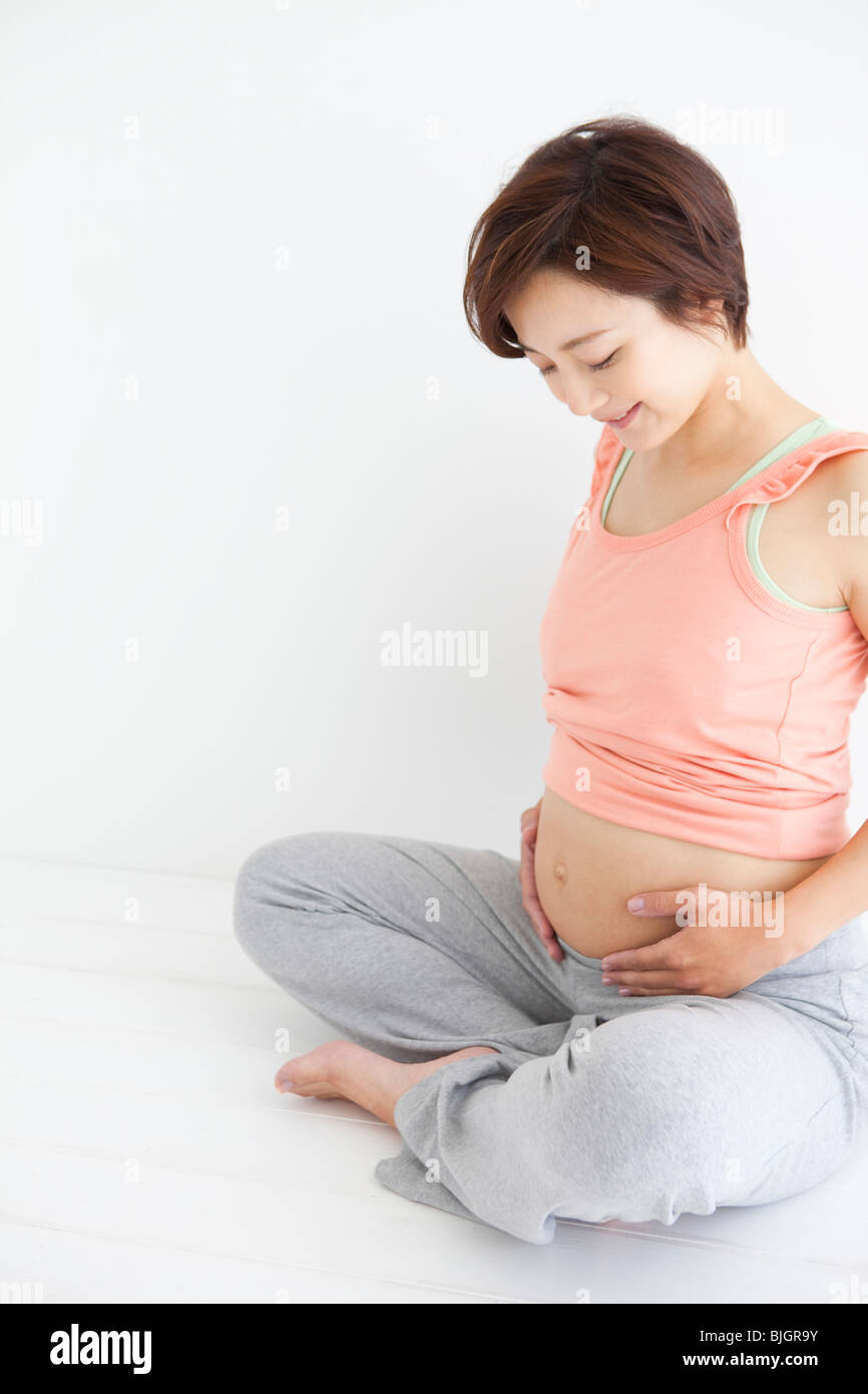 Studio portrait of pregnant woman sitting crosslegged Stock Photo Alamy