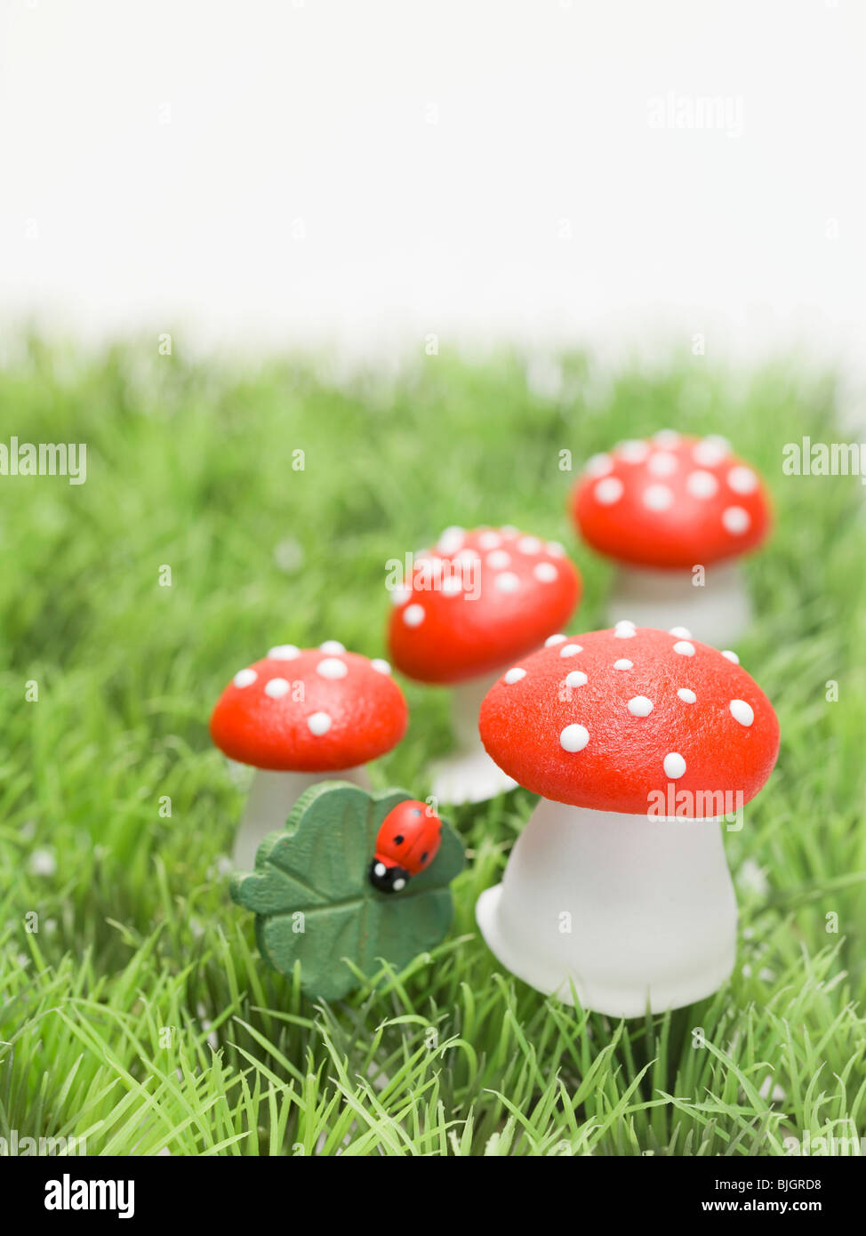 Lucky charms (fly agaric mushrooms, 4-leaf clover) in grass - Stock Photo