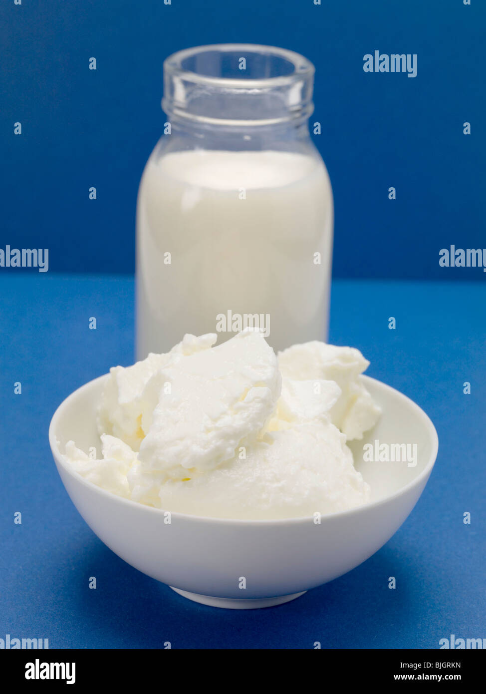 Quark in small white bowl in front of bottle of milk - Stock Photo
