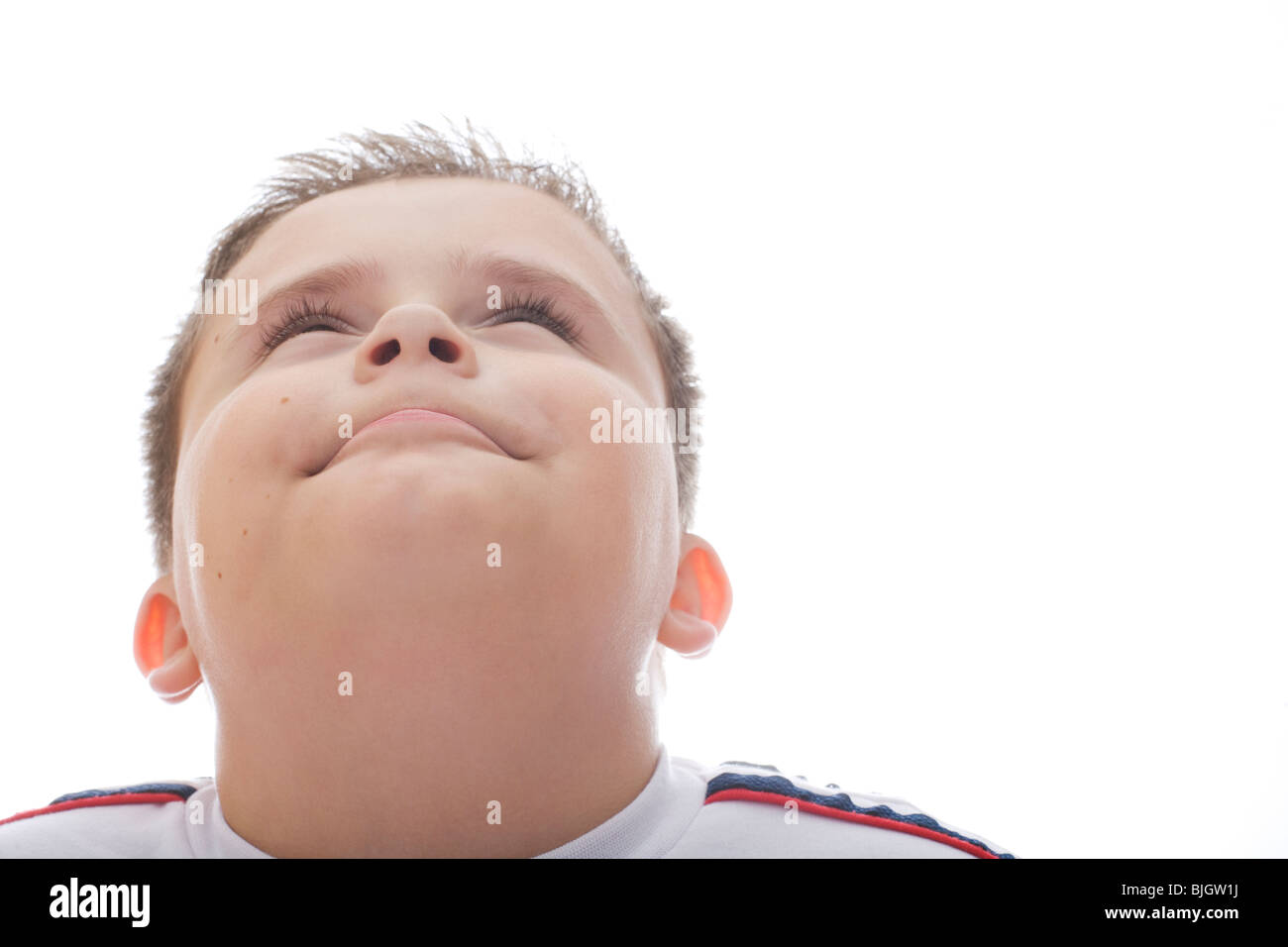 A young boy looking up smiling wearing a football shirt. Stock Photo