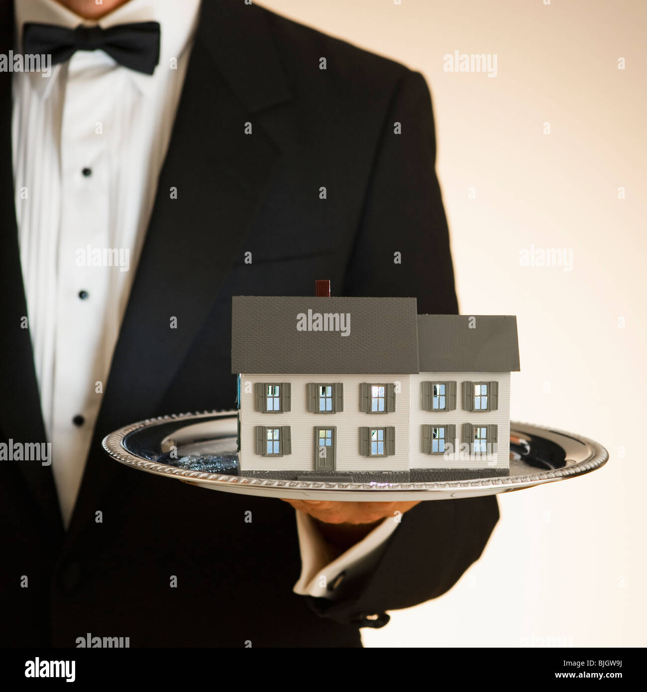 Butler holding toy house on tray Stock Photo