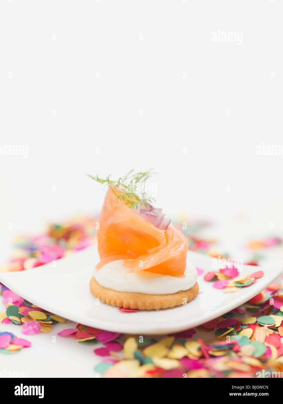 Smoked salmon on cracker on plate surrounded by confetti Stock Photo