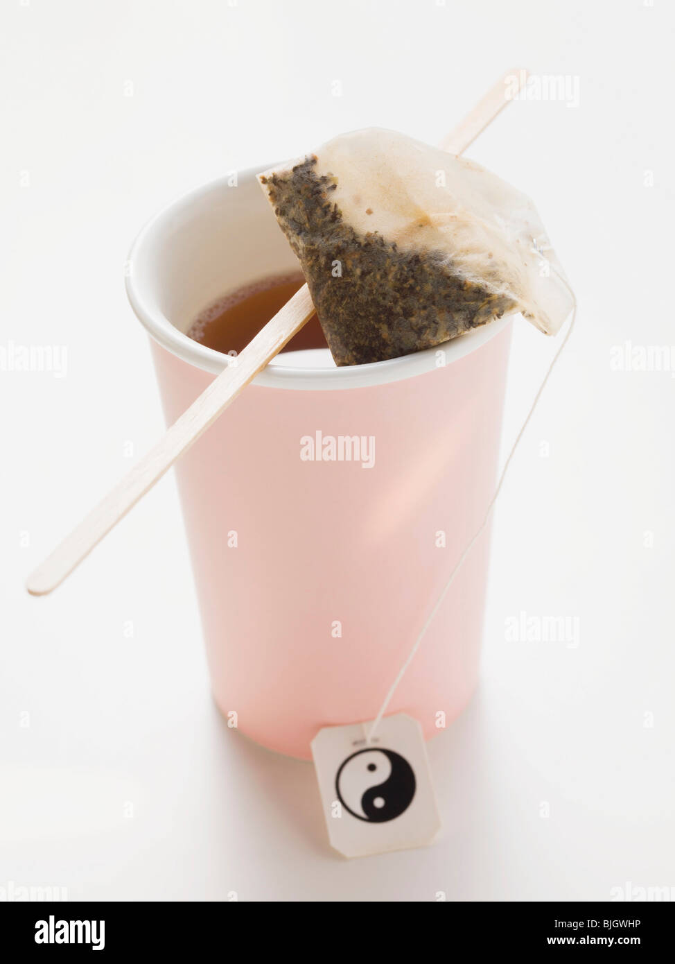 Tea in pink plastic cup with tea bag - Stock Photo