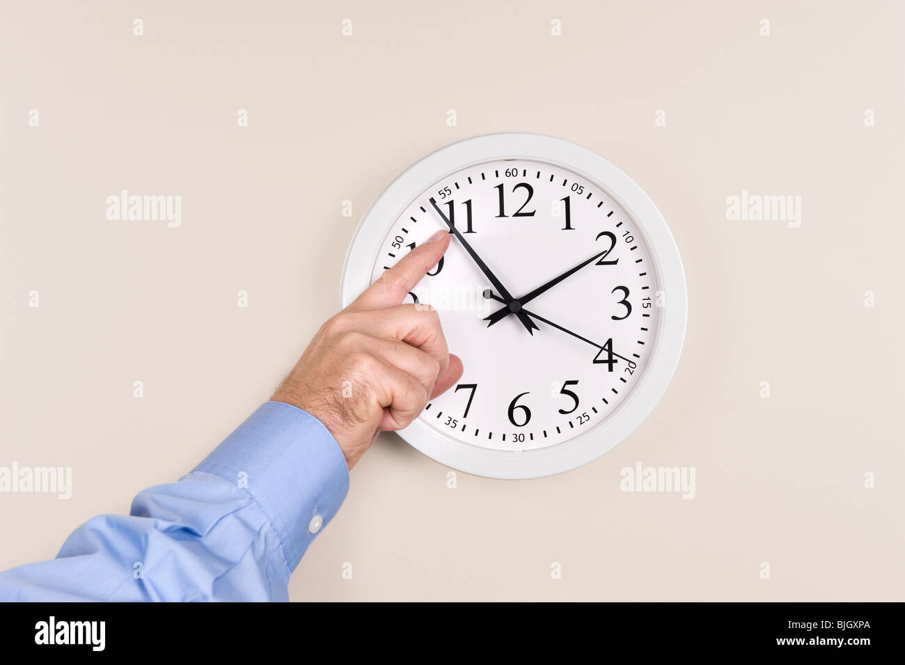 A man changes the time on a clock, moving it forward in time, spring forward. Stock Photo