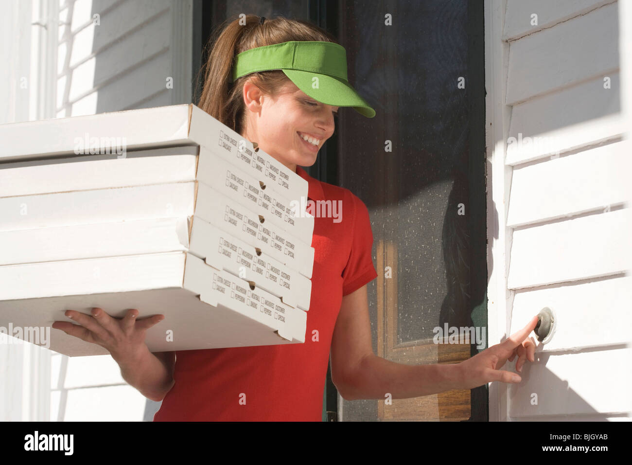 Pizza delivery girl ringing doorbell - Stock Photo