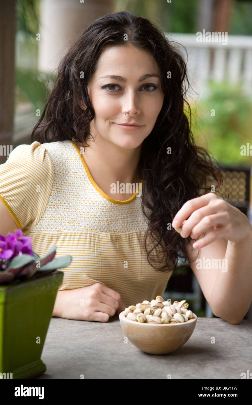woman eating a bowl of nuts Stock Photo