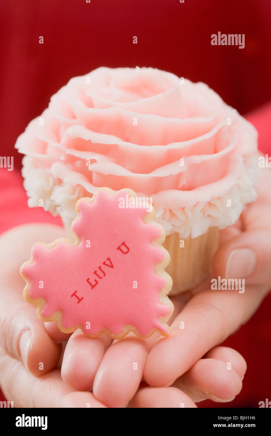 Hands holding cupcake and Valentine's Day biscuit - Stock Photo