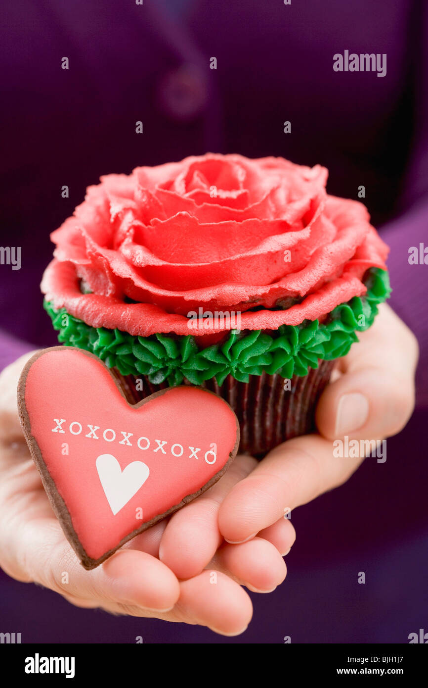 Hands holding cupcake and XOXO biscuit - Stock Photo