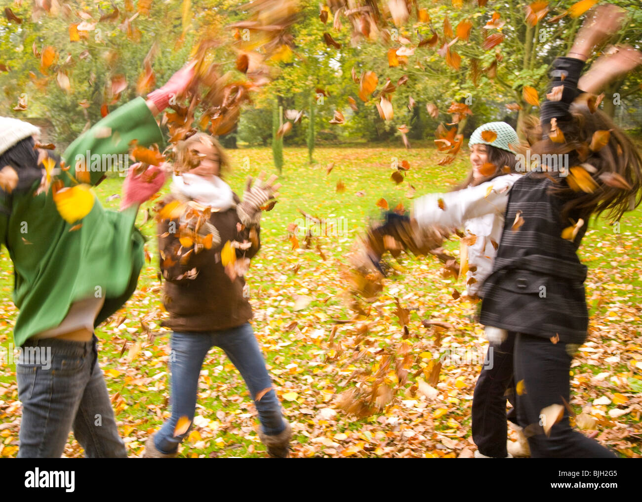 Young girls playing with leaves in the park Stock Photo - Alamy