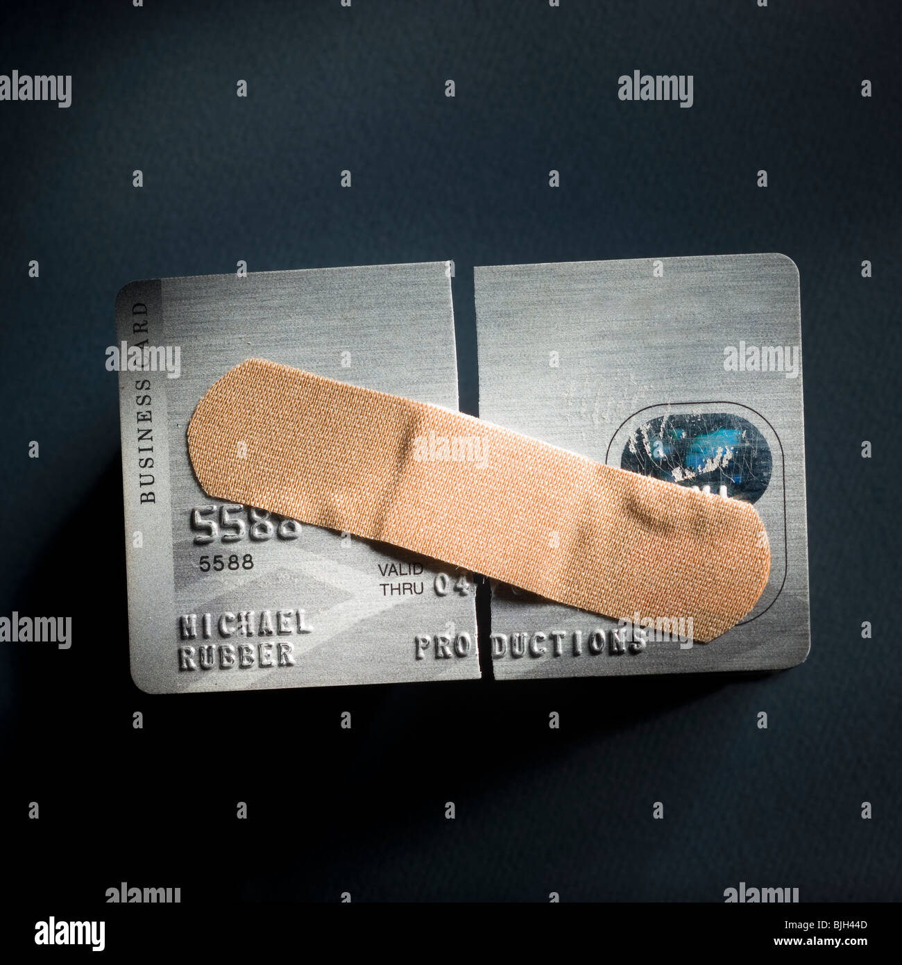 credit card cut in half with a band-aid holding it together Stock Photo