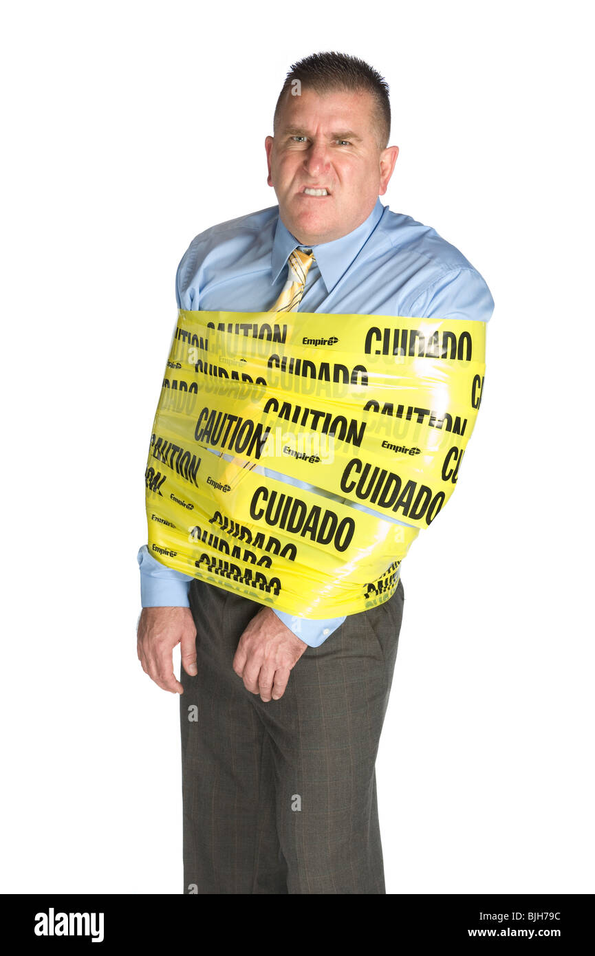 An angry businessman wrapped in caution tape as a warning to coworkers snarls as a result of stress and frustration Stock Photo