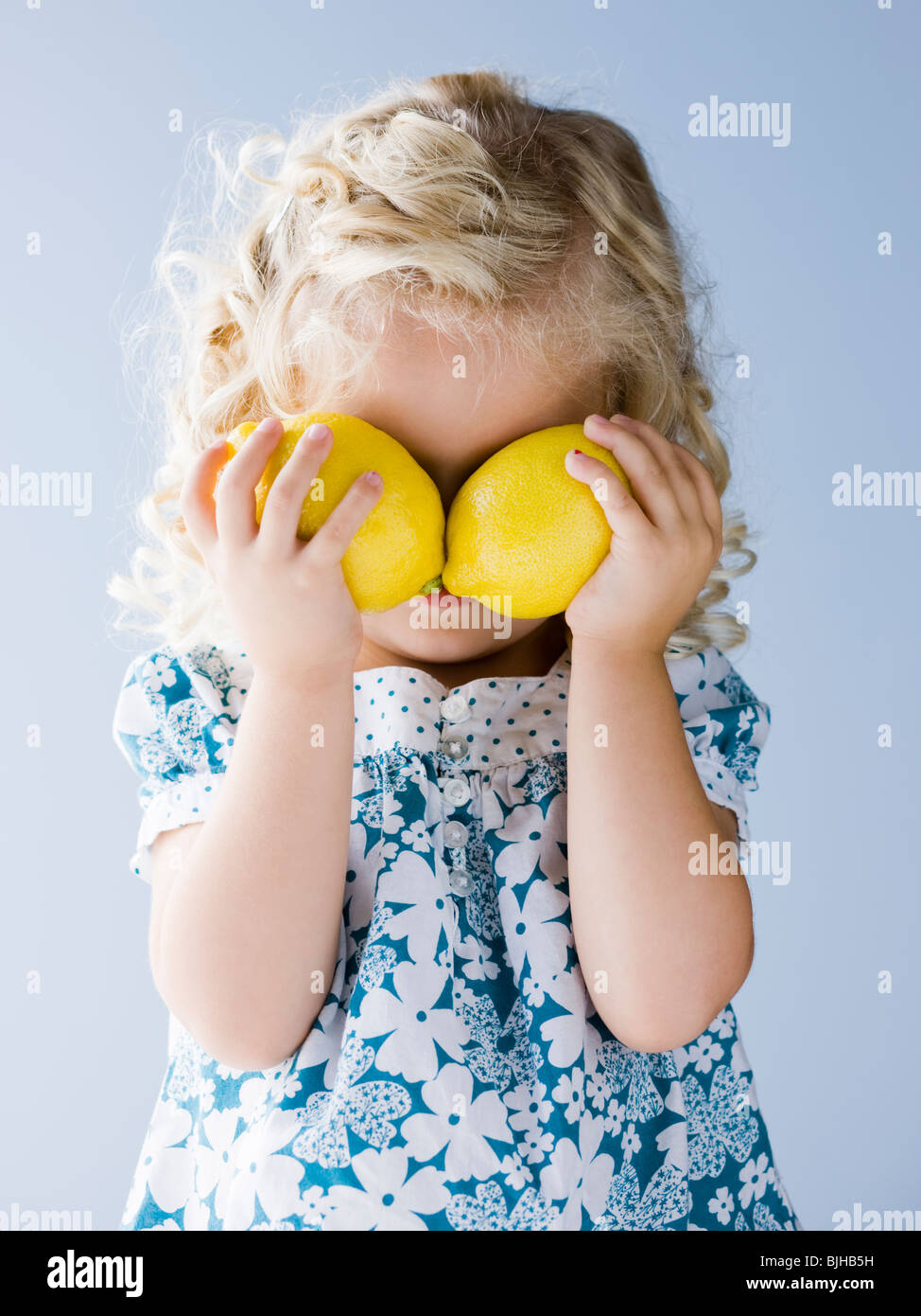 little girl holding lemons in front of her eyes Stock Photo Alamy