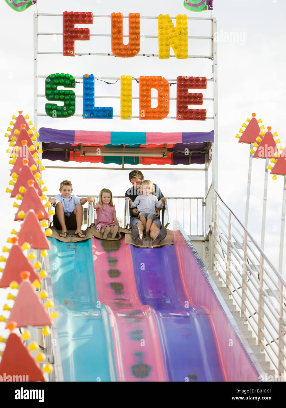 family at the carnival riding on the fun slide together Stock Photo Alamy