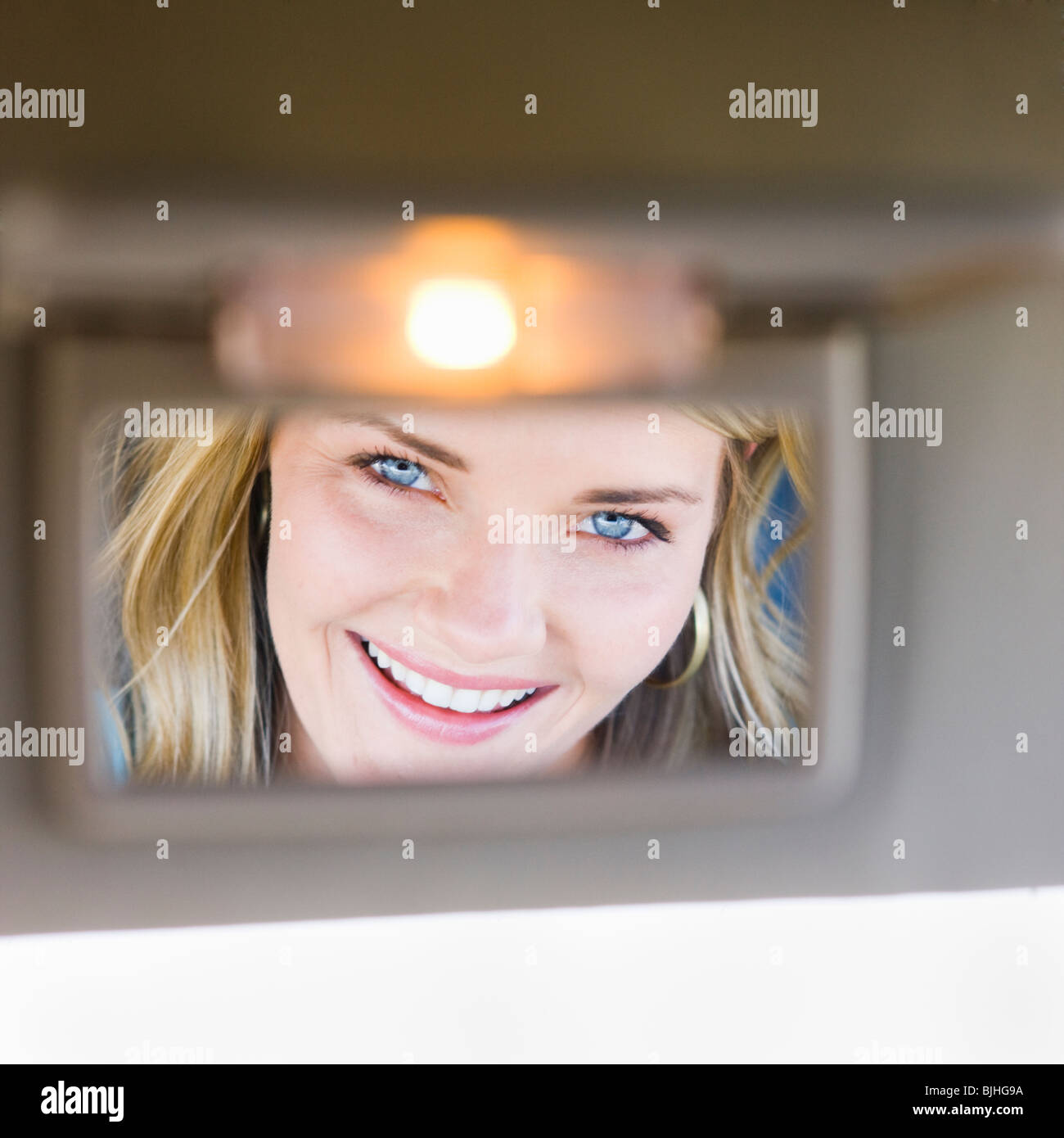 woman looking in visor mirror in car Stock Photo Alamy