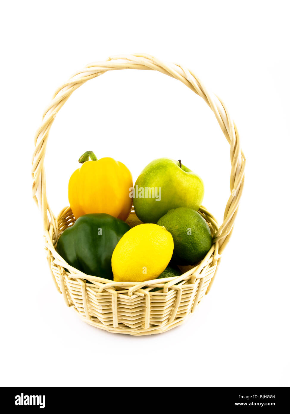 Lemons, limes, paprika and apple in basket on white background Stock Photo