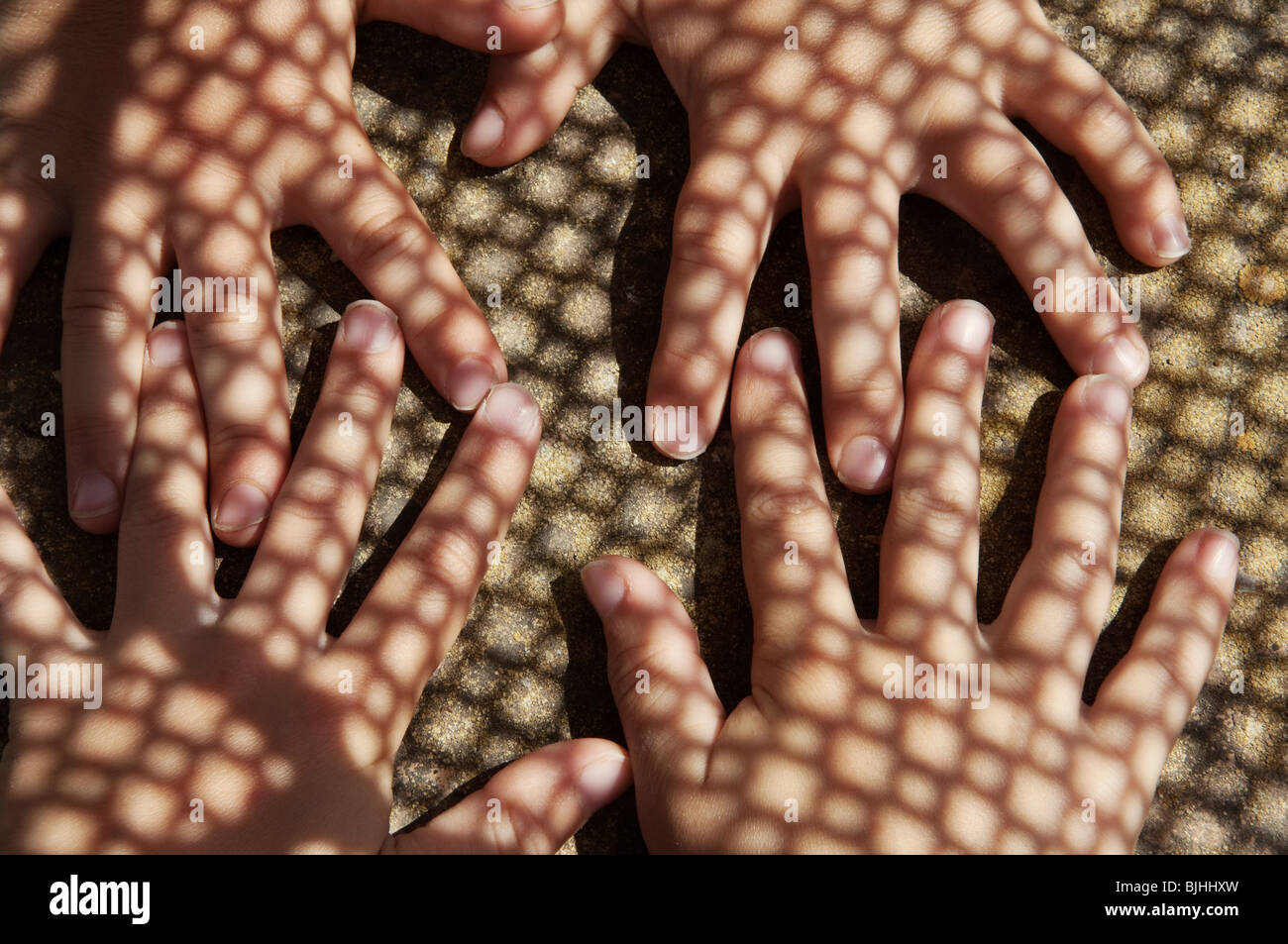 childrens hands touching under shadow pattern Stock Photo