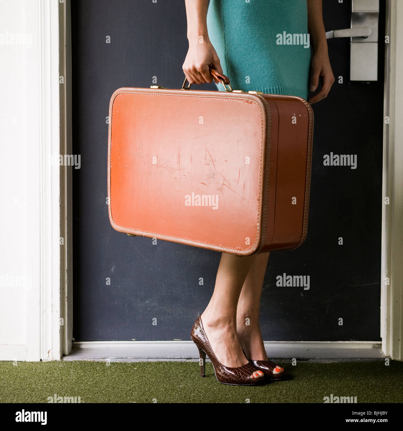 woman carrying a suitcase outside a door Stock Photo Alamy