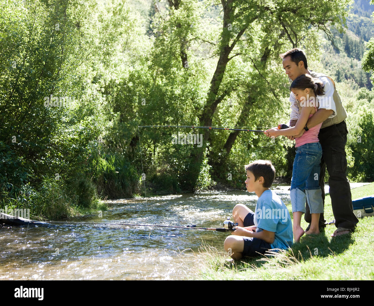 dad teaching his children to fish Stock Photo - Alamy