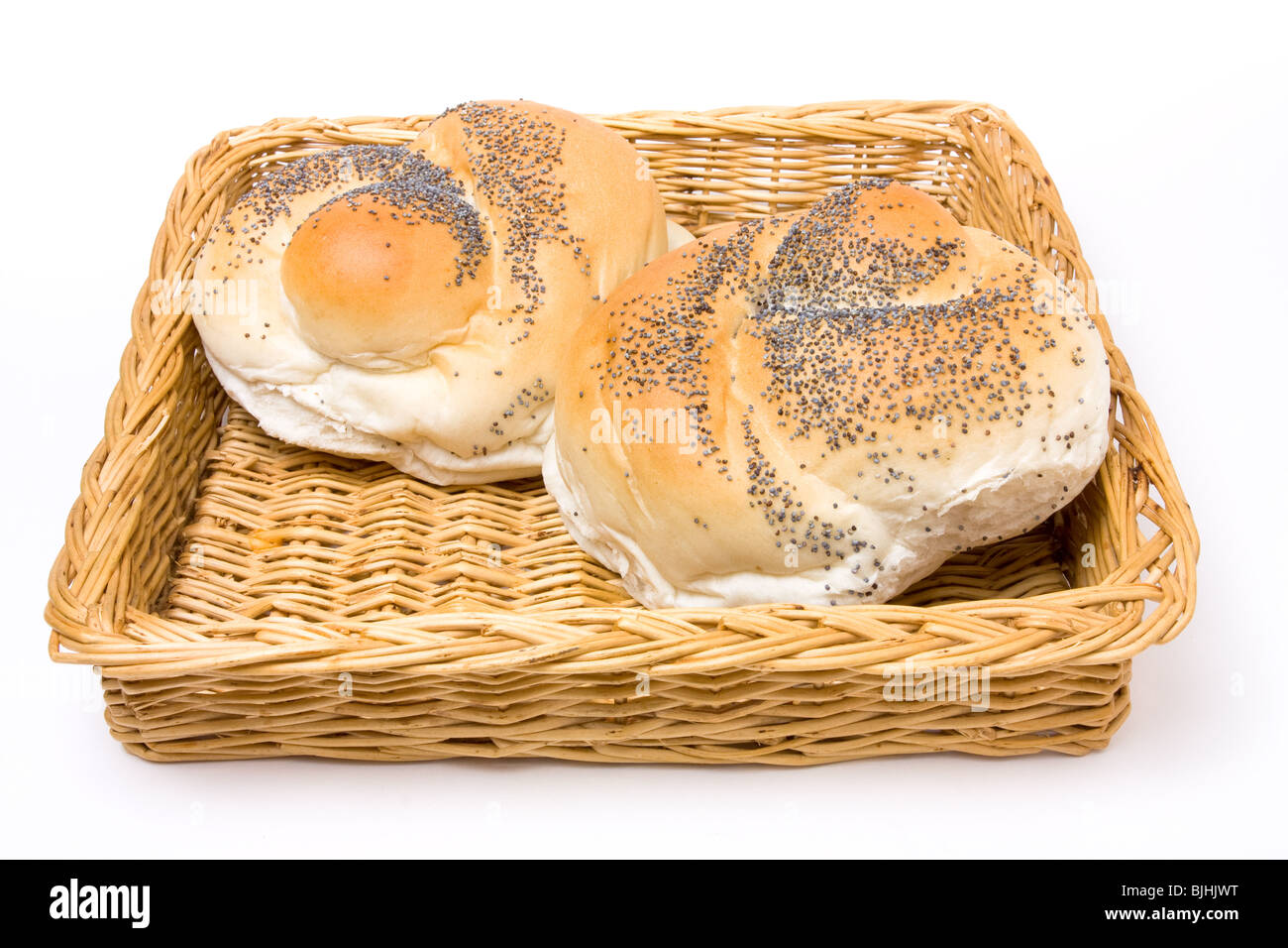 Seeded bread roll in wicker basket from low viewpoint isolated against white background. Stock Photo