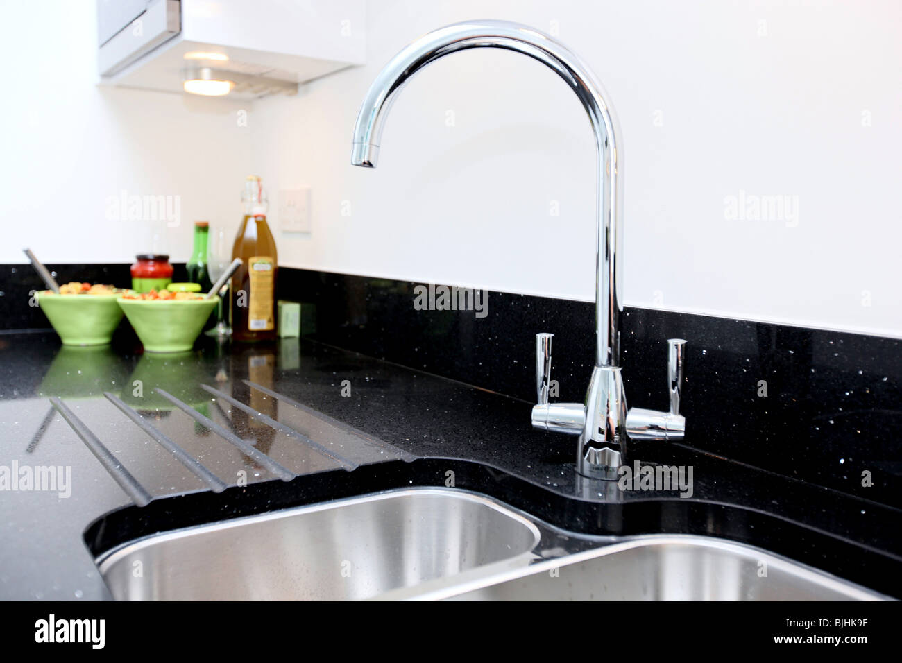 High key close up image of a modern kitchen interior with the main focus on the chrome tap and granite worktop. Stock Photo