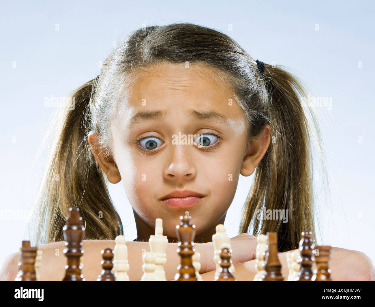 girl looking at a chess set with disbelief Stock Photo