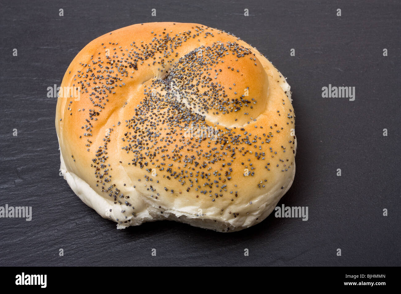 Seeded bread roll from high viewpoint against dark slate background. Stock Photo
