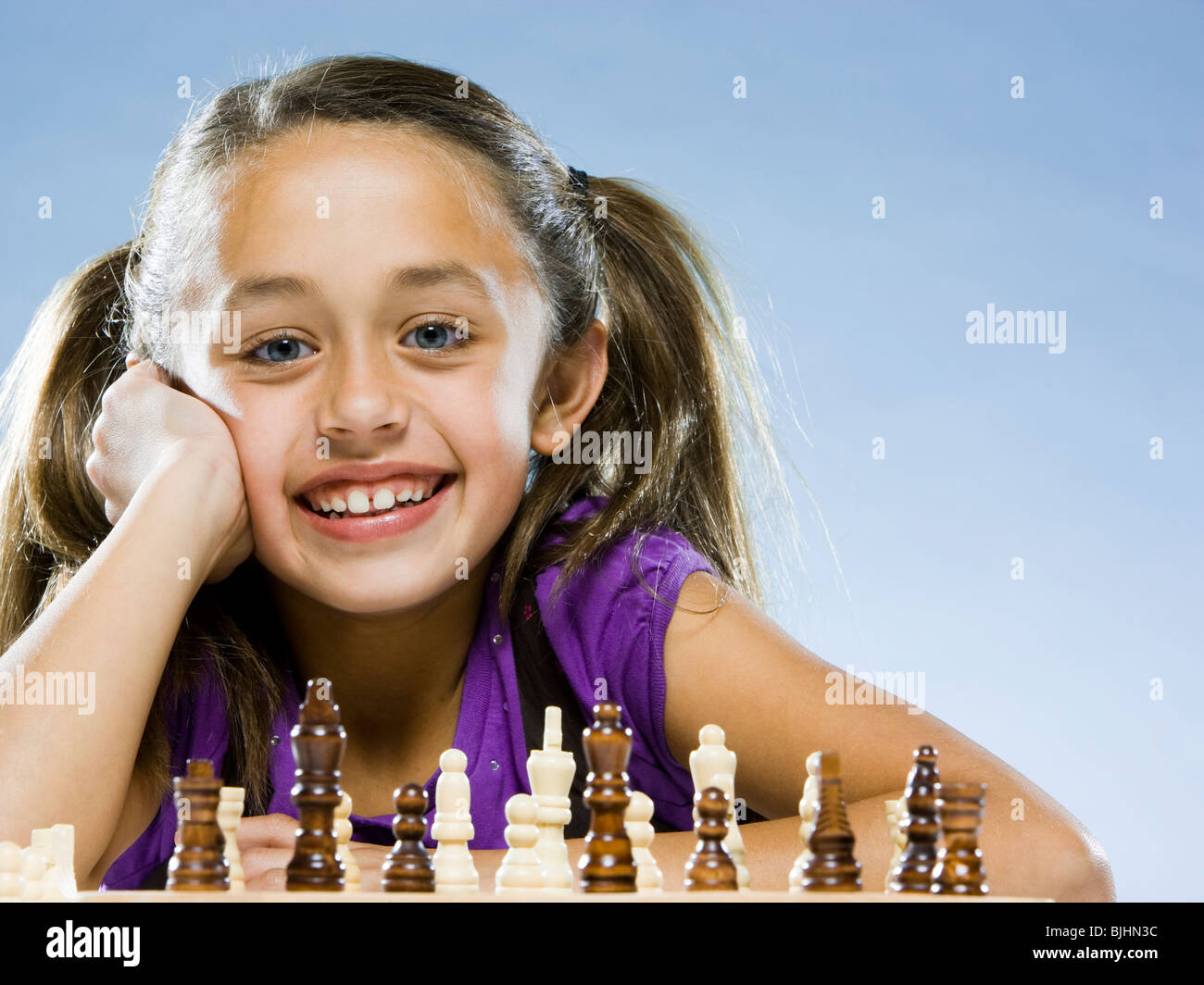 girl looking at the camera while sitting at a game of chess Stock Photo