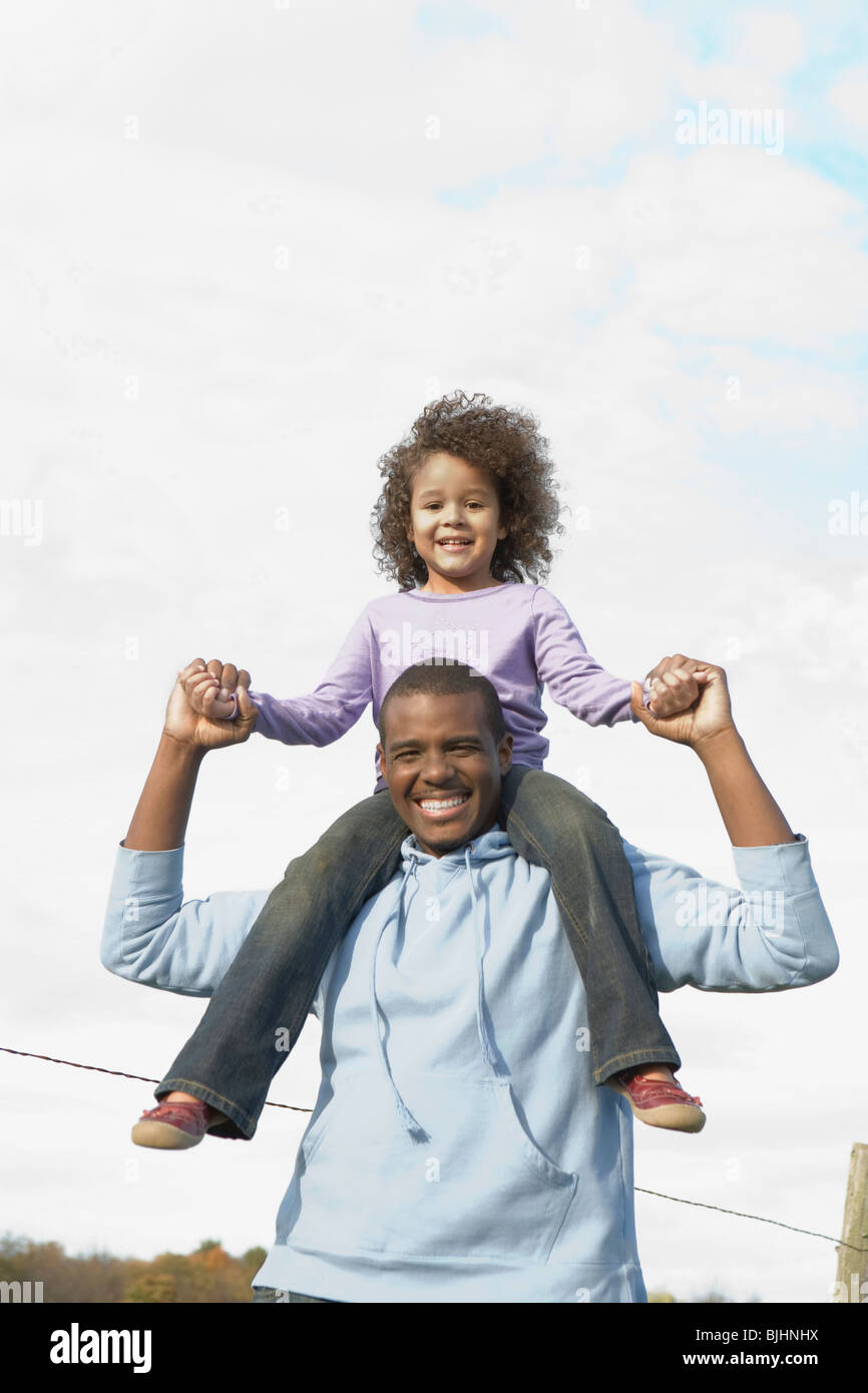 Man carrying daughter on his shoulders Stock Photo