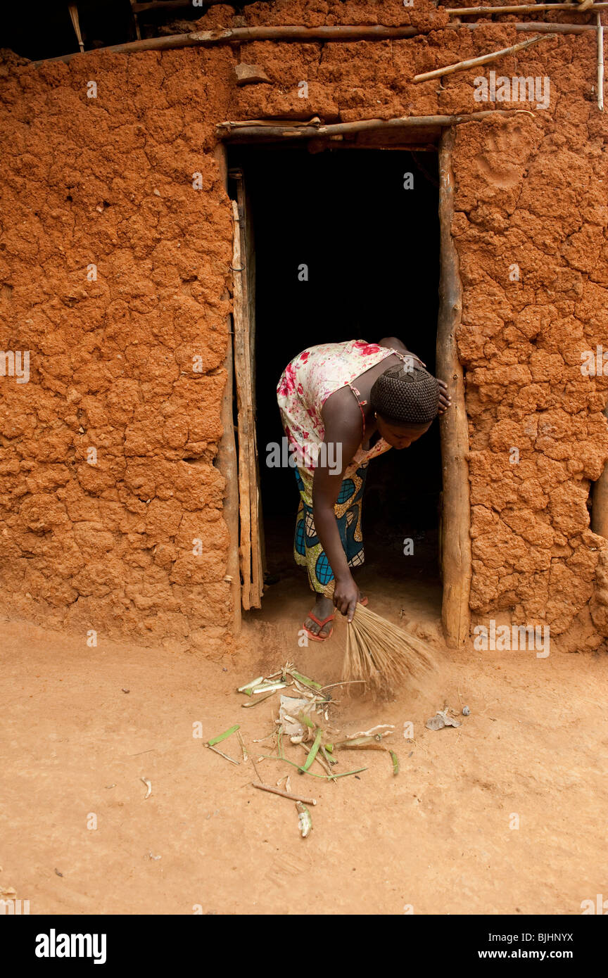 Lady brushing out house with brush made out of dried grass. Rwanda Stock Photo