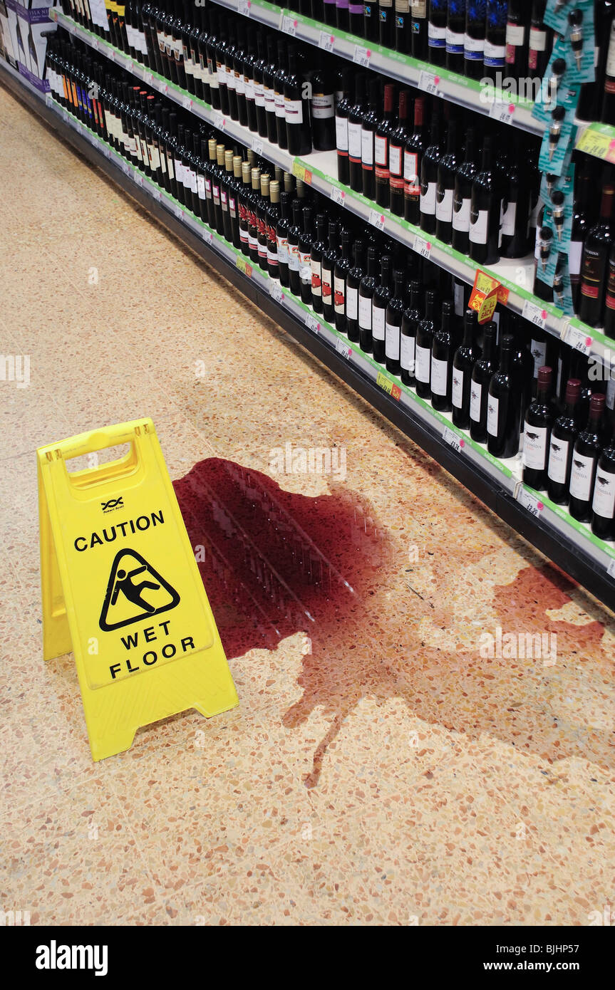 Broken bottle of spilt red wine on supermarket floor Stock Photo