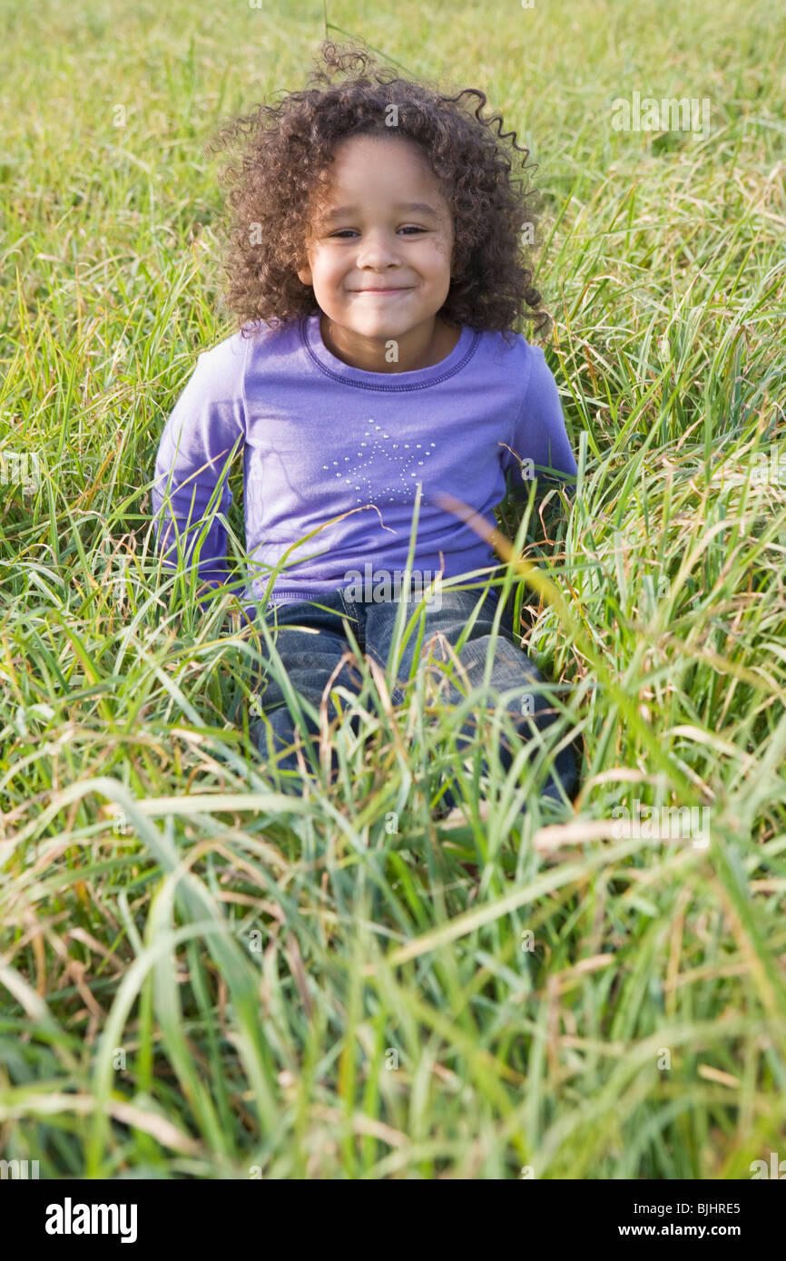 Young girl sitting in tall grass Stock Photo
