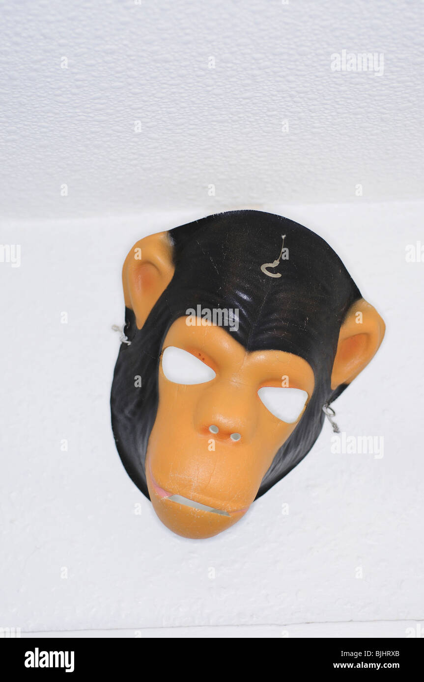 Unused monkey mask hanging from wall Stock Photo