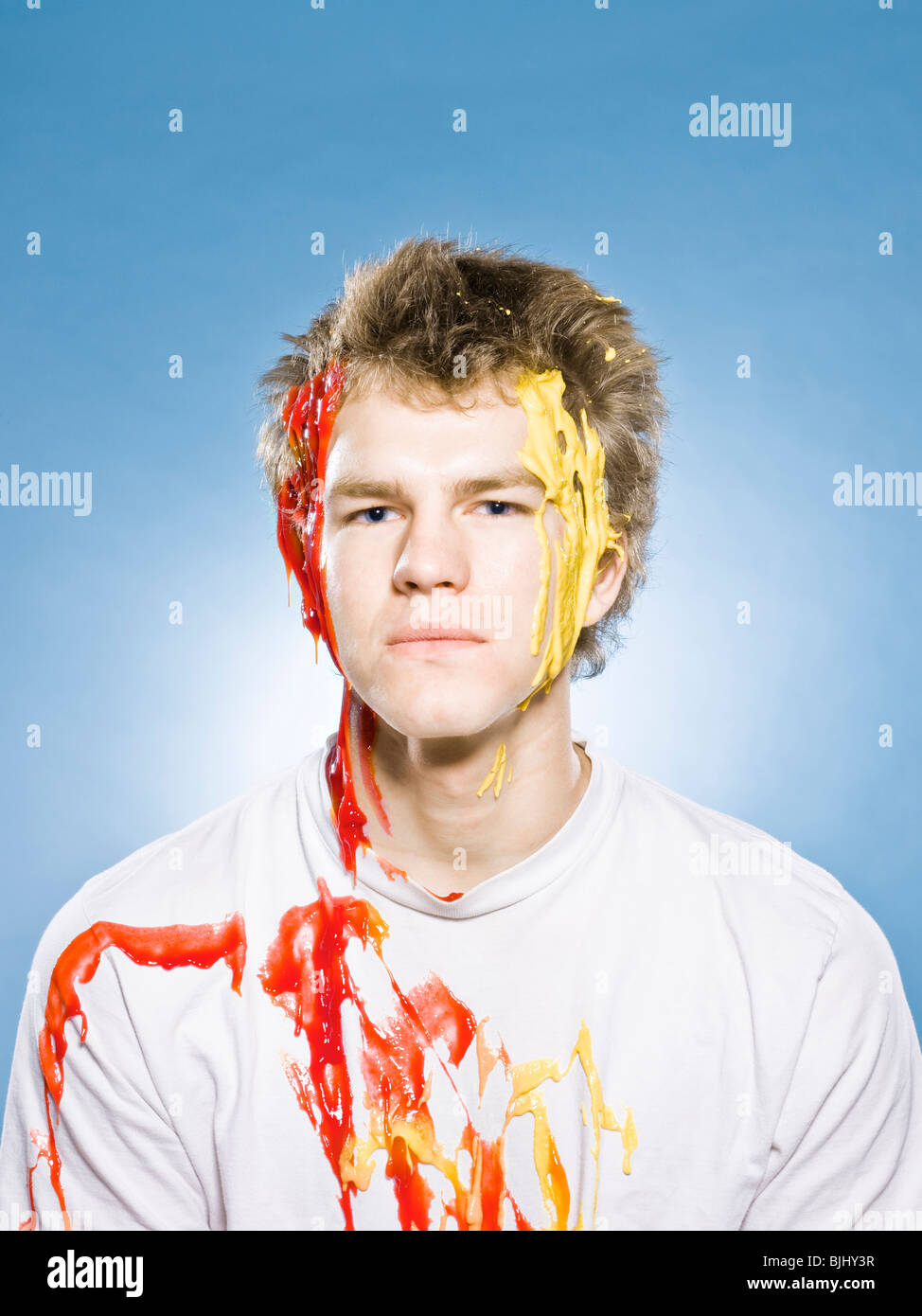 man being squirted with ketchup and mustard Stock Photo Alamy