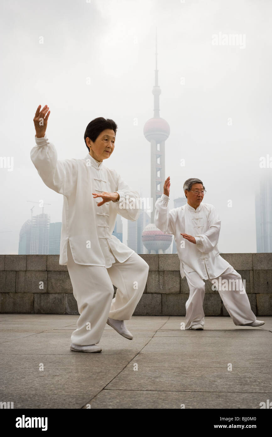 Couple doing tai chi outdoors with city skyline in background Stock Photo