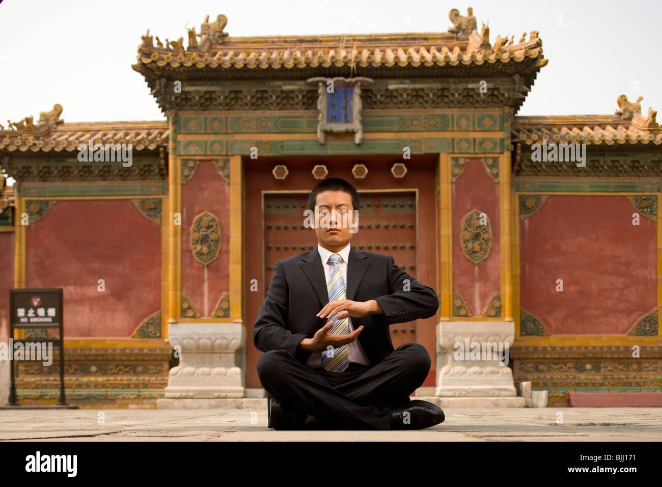 Businessman sitting cross legged outdoors meditating Stock Photo - Alamy