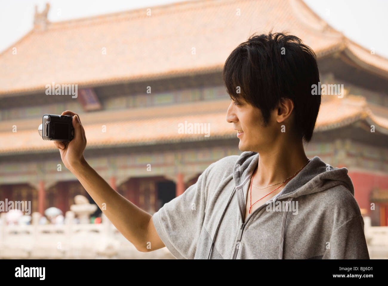 Teenage boy outdoors with digital camera smiling Stock Photo