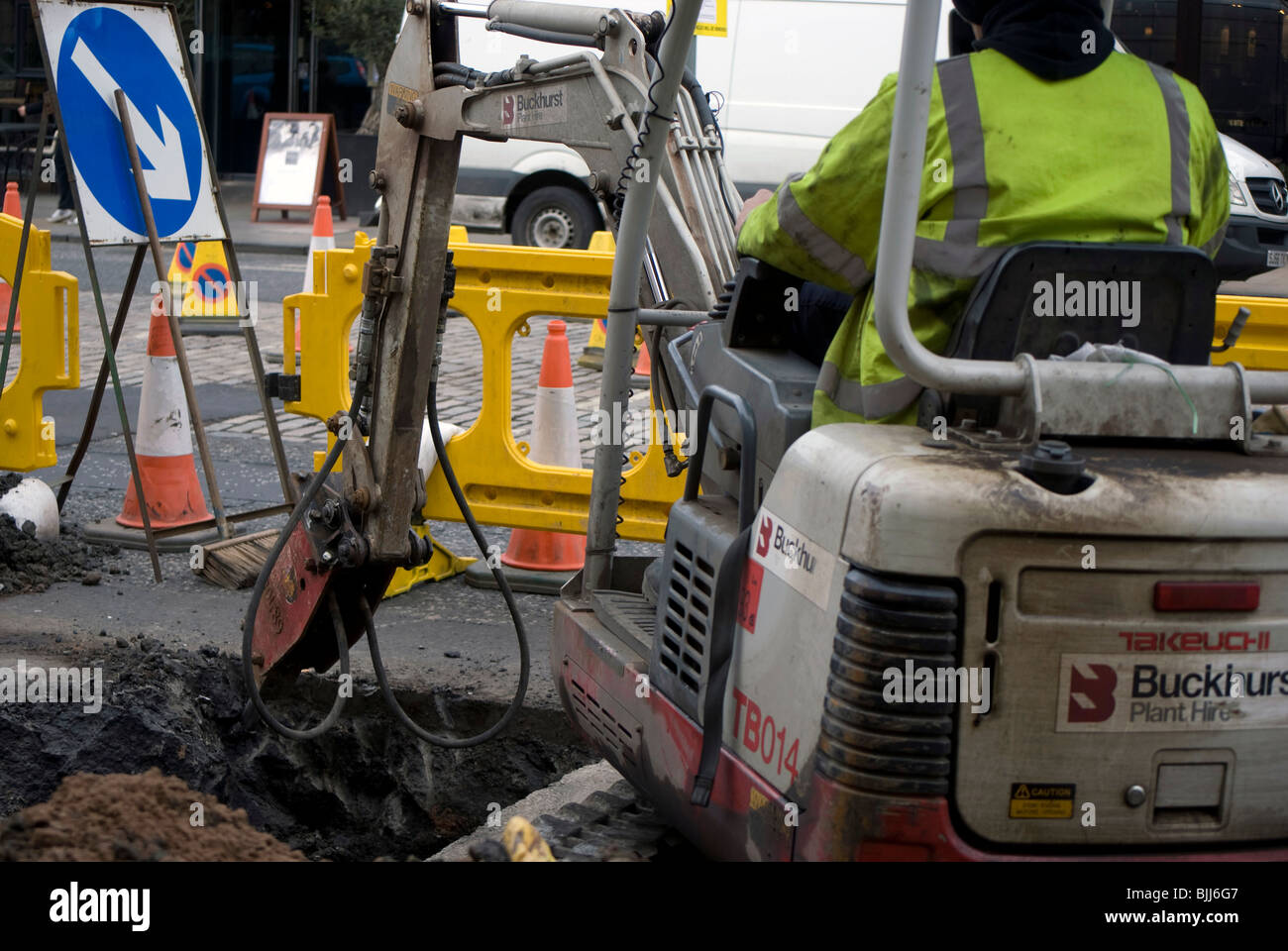 Hydraulic drill attachment on a digger digging a hole in the road Stock
