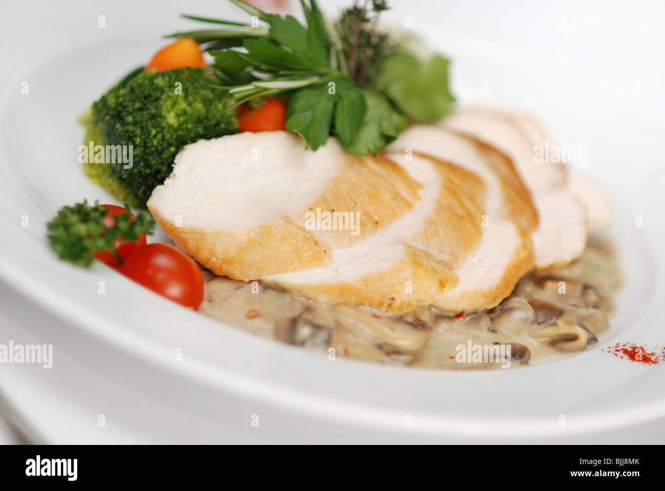 Chicken filled served with chanterelle sauce, rice and vegetables garnish in restaurant Stock Photo