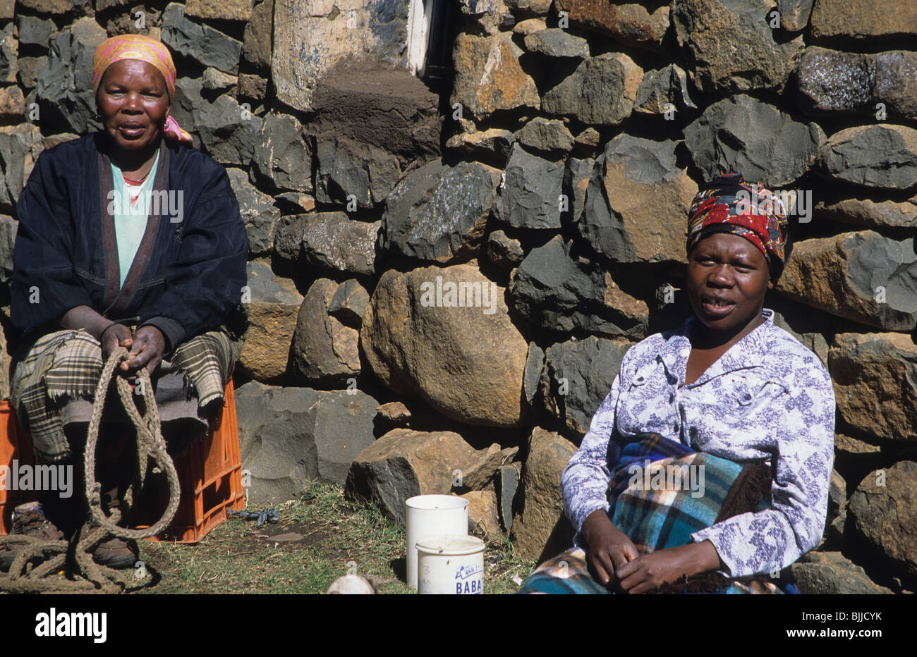 Women hang out in front of their traditional stone home, Semonkong, Lesotho, Southern Africa Stock Photo