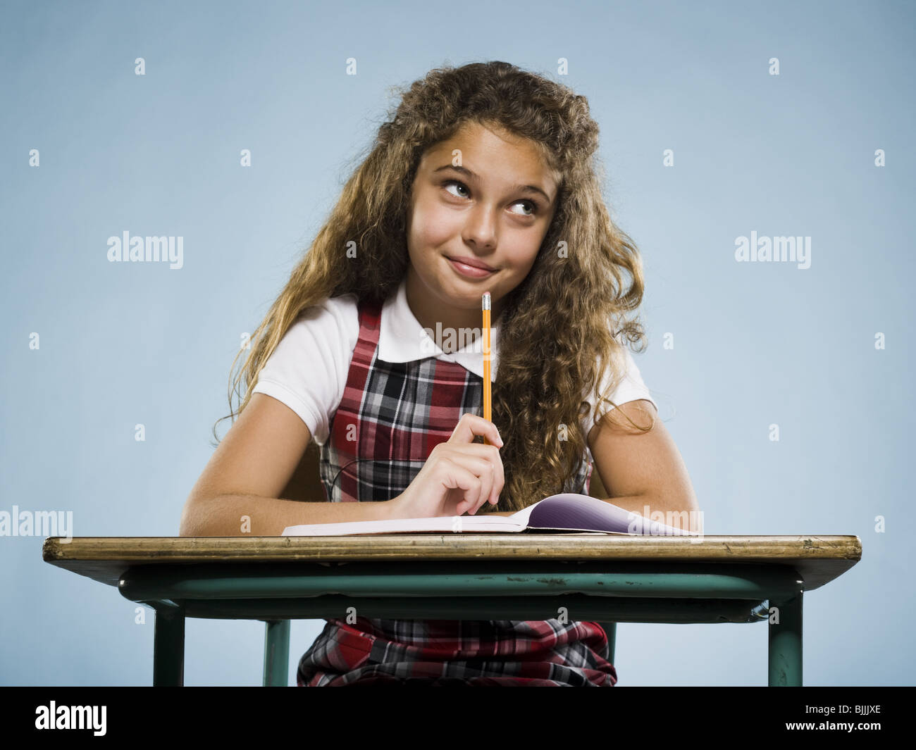 Girl sitting at desk with workbook looking bored Stock Photo - Alamy