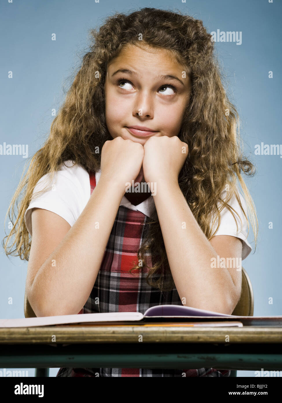 Girl sitting at desk with workbook looking bored Stock Photo - Alamy